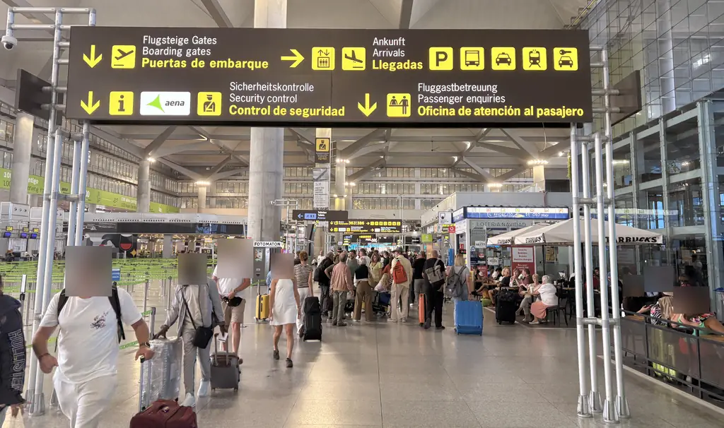 Signs in the departures hall at Málaga Airport pointing to the boarding gates, arrivals, security control and the passenger service office